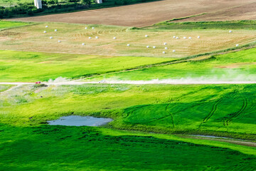 Vehicle driving on unpaved road making dust through the wonderful and beautiful rural scenic landscape,Avena Sativa,Oat green field.