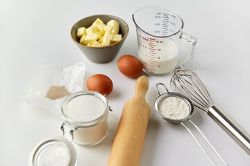 cooking food and culinary concept - rolling pin, butter, eggs, flour and cane sugar on table