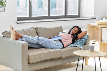 people and leisure concept - african american woman sleeping on sofa at home
