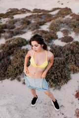 Woman in the beach wearing yellow swimsuit