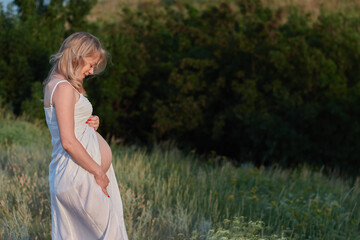 Pregnant woman in white dress posing in the park