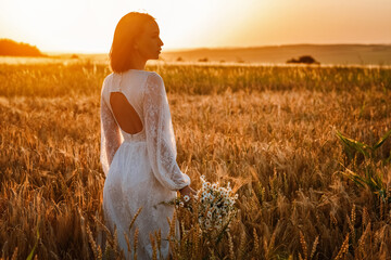 Beautiful woman in a white dress with a bouquet of flowers in a wheat field at sunset. Free lifestyle concept © Валентина Баранова