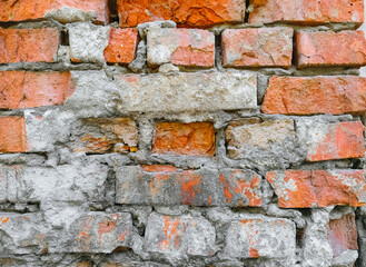 The texture of an old wall of red, orange uneven bricks with gray cement and concrete. Photography,...