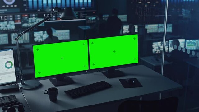 Two Digital Computer Screens with a Green Mock Up Chromakey in Modern Monitoring Office. Control Room with Specialists and Managers Sit in Front of Computers. 