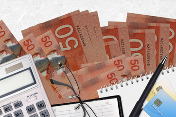 50 Canadian dollars bills and calculator with glasses and pen. Tax payment concept or investment...