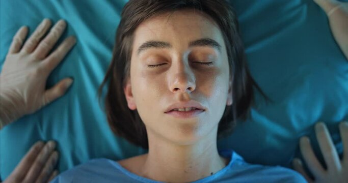 Close up of millennial girl coming to her senses while lying on hospital stretcher.Top view of female teenager opening eyes in ambulance. Concept of healthcare and illness