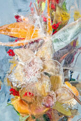 Obraz na płótnie Canvas Frozen bouquet of orange flowers inside the ice block on gray background