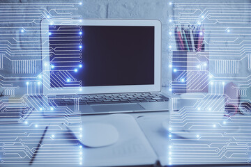 Computer on desktop in office with technology theme hologram. Double exposure. Tech concept.