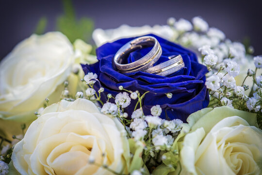 Eheringe auf blauen Rosen im Brautstrauß hübsch platziert