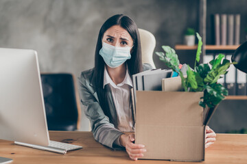 Photo of frustrated sad upset girl marketer agent representative sit desk table lost job corona virus quarantine company crisis wear medical mask in workplace workstation