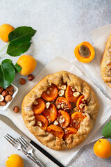 Healthy pastries made from rye flour, dessert diet food. Galette with apricots and nuts on a light stone table. Top view flat lay background. Copy space.