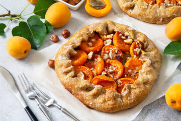 Healthy pastries made from rye flour, dessert diet food. Galette with apricots and nuts on a light stone table.