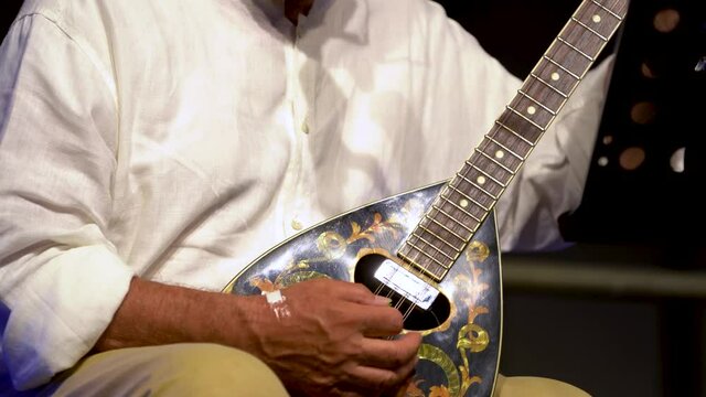 elderly man plays mandolin during a live concert. Freehand shooting. ideal for aging concept. New life in retirement
