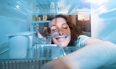 Happy woman cooling herself in the fridge