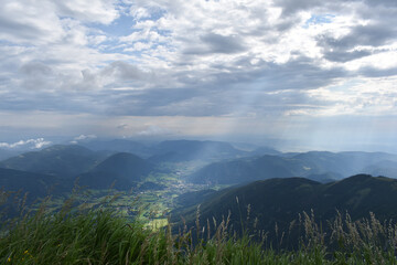Fototapeta premium Sonnenstrahl durch dunkle Wolken im Gebirge, Sonne und Wolken in den Bergen, Berge bis zum Horizont, Erkenntnis und Inspiration 