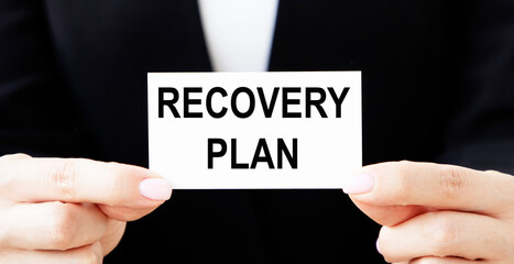 Business girl removes a business card in her pocket with the inscription RECOVERY PLAN.