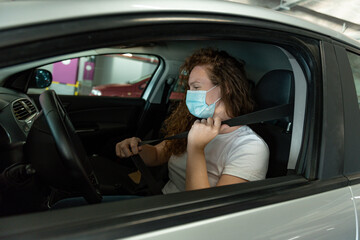 Adult Woman with protective mask driving a car to shopping. Infection prevention and control of epidemic. World pandemic.