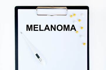 On the table are, a thermometer, a pen and a notebook with the inscription -Melanoma. The concept of medicine.