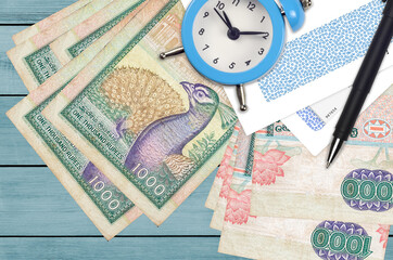 1000 Sri Lankan rupees bills and alarm clock with pen and envelopes. Tax season concept, payment deadline for credit or loan. Financial operations using postal service