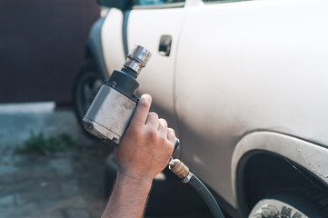 A man holds a pneumatic wrench in his hands. Car maintenance and repair in the garage.