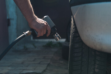A man holds a pneumatic wrench in his hands. Car maintenance and repair in the garage.