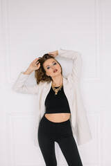 Naklejka premium Woman in a white jacket near a white wall is stylishly dressed