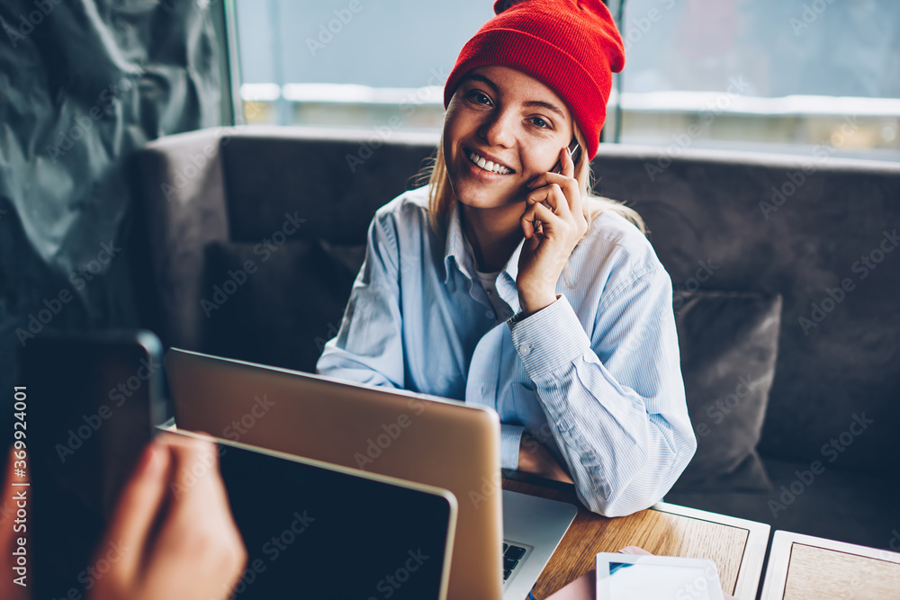 Poster portrait of successful female freelancer in stylish red hat talking calling to mobile operator and t