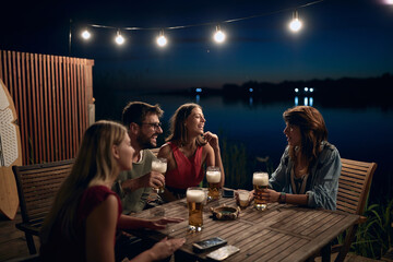 group of friends sitting outdoor by the river, drinking beer - Powered by Adobe