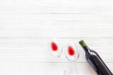 Wine bottle and glasses on white wooden background from above copy space