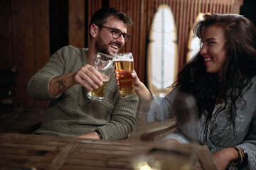 young adult  couple toasting with glasses of beer