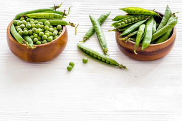 Set of green pea pods in wooden bowl on kitchen table desk