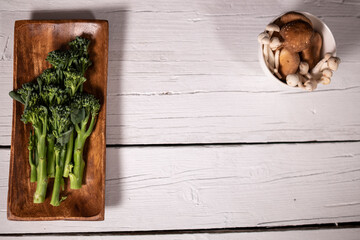 variety of mushrooms on white plate and broccoli on wooden plate for cooking in vegan food