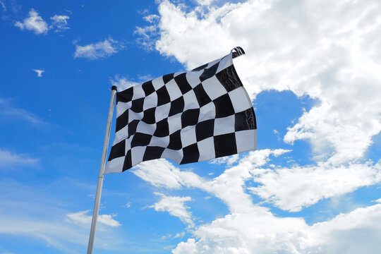 Checkered flag old condition on flagpole waving in the wind with clouds on background , by adjusting the focus the flagpole of the image The concept of flags are waving and moving.