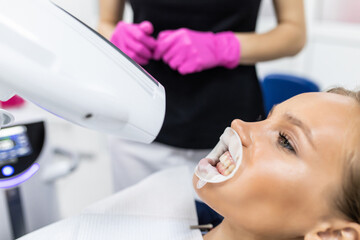 Teeth whitening for woman in dentist office. Bleaching of the teeth at dentist clinic.