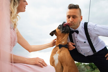Creative hipster wedding by the sea. The bride is in a pink dress and veil, the groom is in...