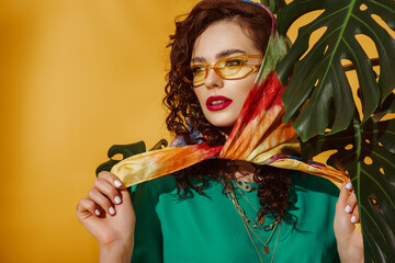 Summer fashion concept: woman wearing yellow sunglasses, colorful kerchief, has fuchsia color lips,...