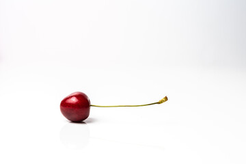 One piece of red cherry on a white background. Copy space around  isolated fresh organic sweet cherry berry. Healthy food from nature. Fruits for desserts.