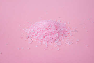 a pile of large sprinkled crystals of pink sea salt close-up on a pink background with space for text. the concept of body care.