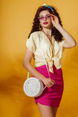 Summer fashion concept: woman wearing yellow linen shirt, fuchsia color mini skirt, purple...