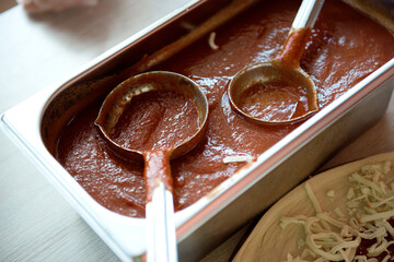 Tomato sauce in a container with ladles, close-up.