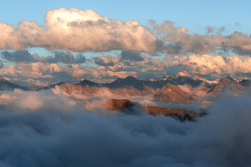 mountain ridge peaks framed by clouds in the evening sun