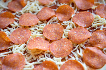 Pieces of pepperoni sausage on a pizza before cooking, close-up.