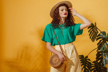 Summer fashion concept: woman wearing trendy green t-shirt, yellow bermudas shorts, straw hat, with...