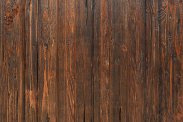 A wall of wooden planks. Brown vertical boards. Rough texture.