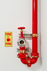 Red fire hydrant inside building on white wall with information sign with text Fire. Fre hydrant...
