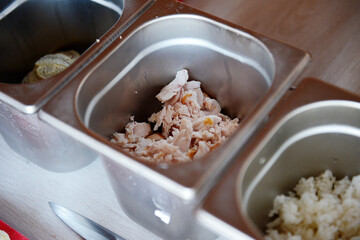 Pieces of smoked chicken in a metal container on the table, close-up.