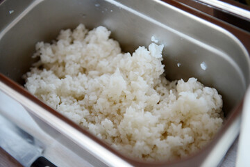 A portion of boiled rice for cooking in a metal container, close-up.