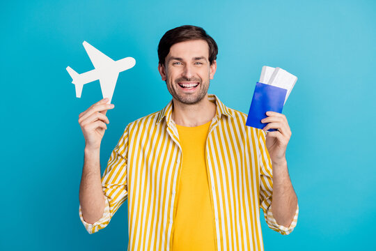 Yeah borders open. Positive cheerful man hold paper card plane tickets enjoy travel abroad covid quarantine wear white outfit isolated over blue color background