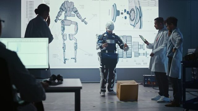 In Development Laboratory: Engineers Look at Robotics Exoskeleton Presentation with Person Lifting and DroppingHeavy Carboard Box, Disappointed Scientists are Upset