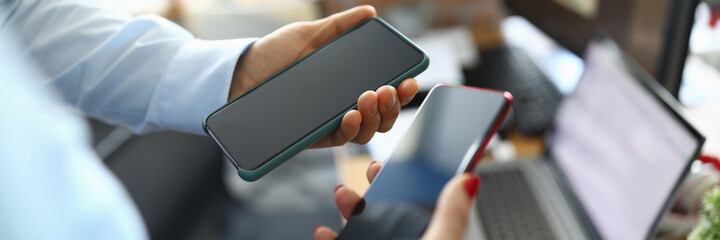 Two modern touch phones are held in hands of office. Development and implementation of new smartphone applications